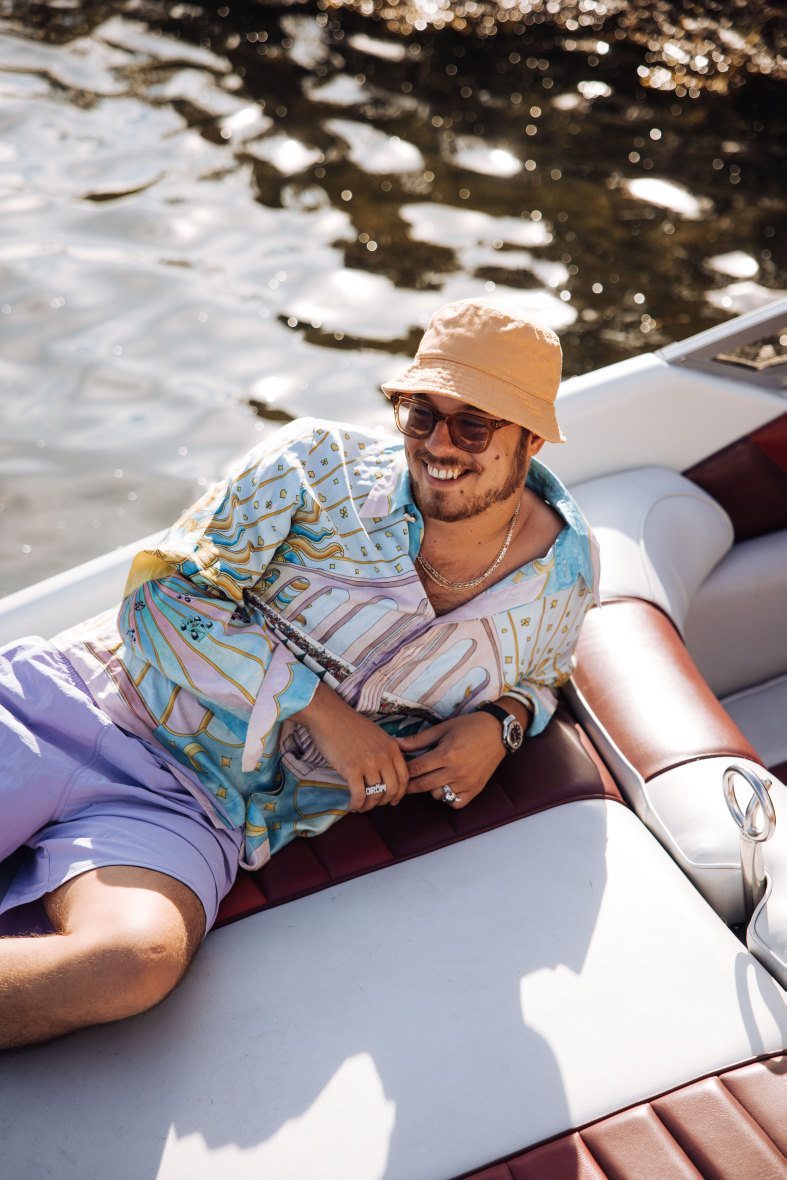 En man med solglasögon som ligger på båten i solen 